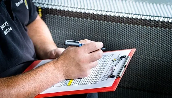 A person writing on a clipboard with a pen.
