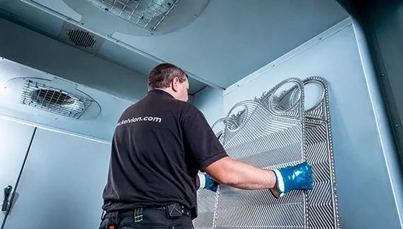 A man in black shirt and blue gloves cleaning a metal cage.
